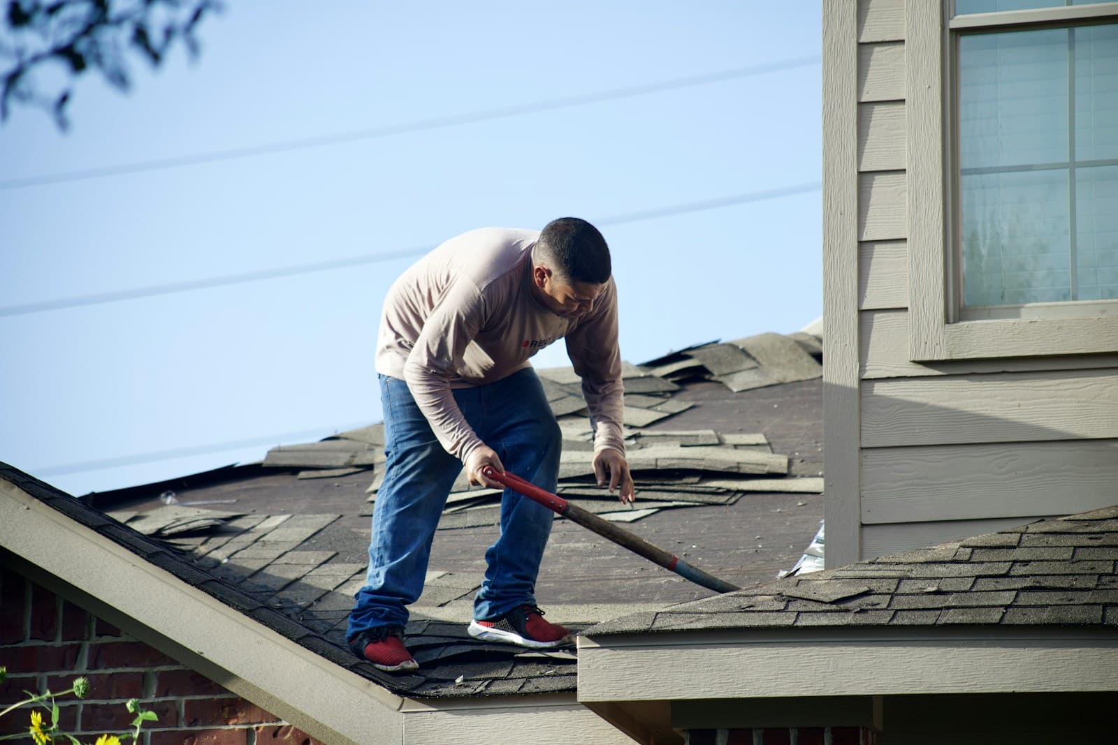 Tearing off storm-damaged shingles before the new roof goes on