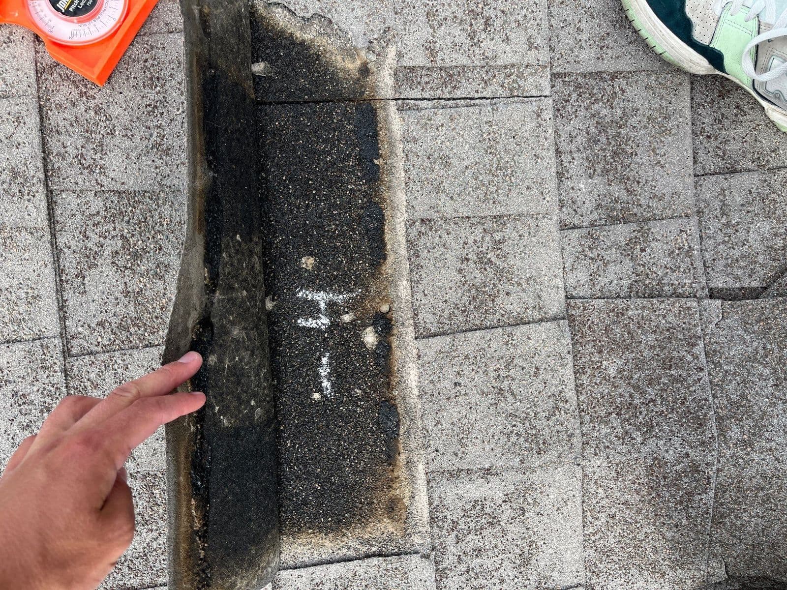 A shingle torn away exposing the layer below