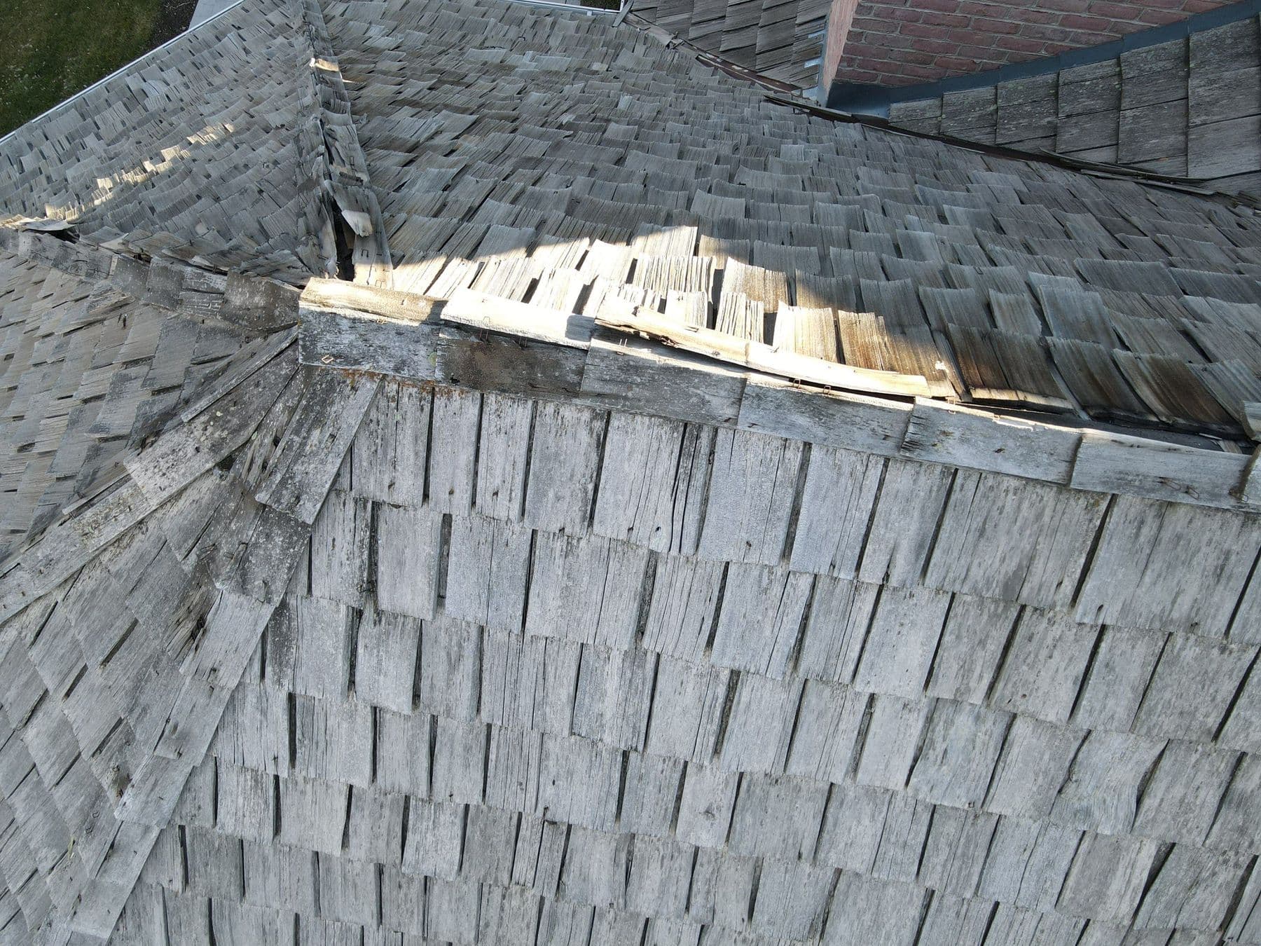 Lifted and broken cedar ridge caps on a weathered shake roof
