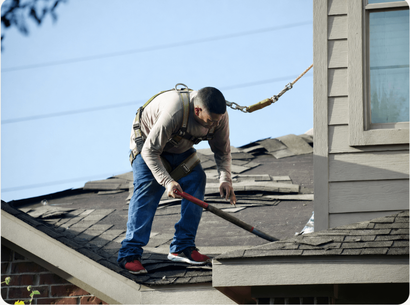 Tearing off storm-damaged shingles before the new roof goes on